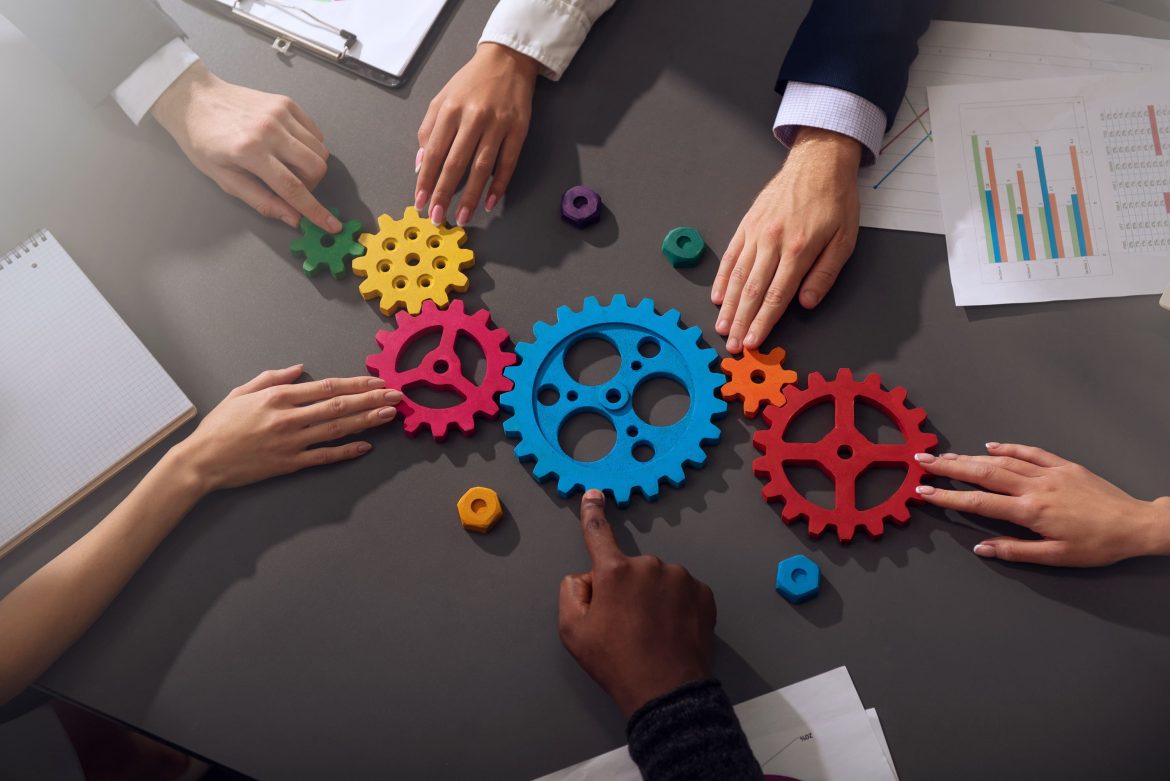 A team collaborates around colorful gears symbolizing the stages of the fund lifecycle in asset management.